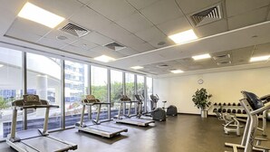A gym with treadmills, elliptical machines, and weight equipment. - LUX  The Silverene Marina View Suite 4 (Dubai)