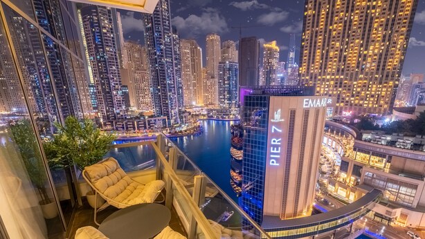 A high-rise hotel with a view of a city skyline at night, featuring a prominent 'PIER 7' building, a pool area, and modern furnishings. - LUX  The Silverene Marina View Suite 4 (Dubai)