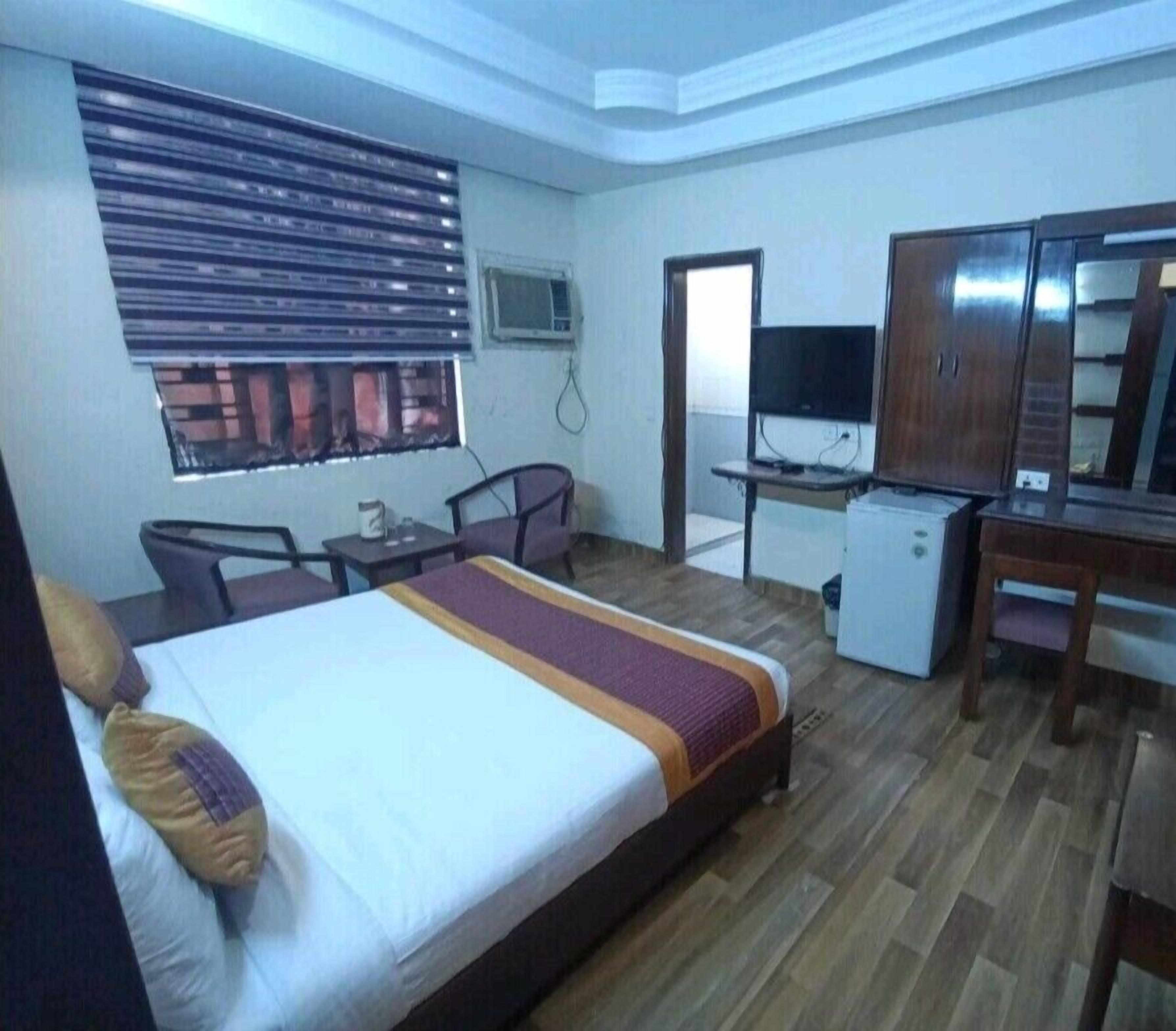 A hotel room with a bed, a desk, a chair, a television, and a wardrobe.