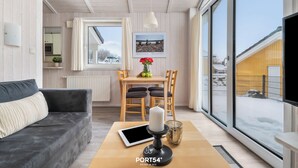 Un salon moderne avec un canapé, une table à manger et des chaises, une grande fenêtre et une vue sur l’extérieur.