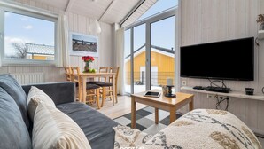 Un salon moderne comprenant un canapé, une table avec un téléviseur et un coin repas avec des chaises et une table.