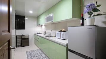 A modern kitchen with green cabinets, a white refrigerator, a microwave, and a sink.