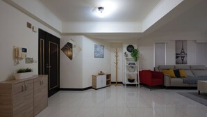 Una sala de estar moderna con un sofá, una mesa de centro, un sillón rojo, una estantería y un perchero.