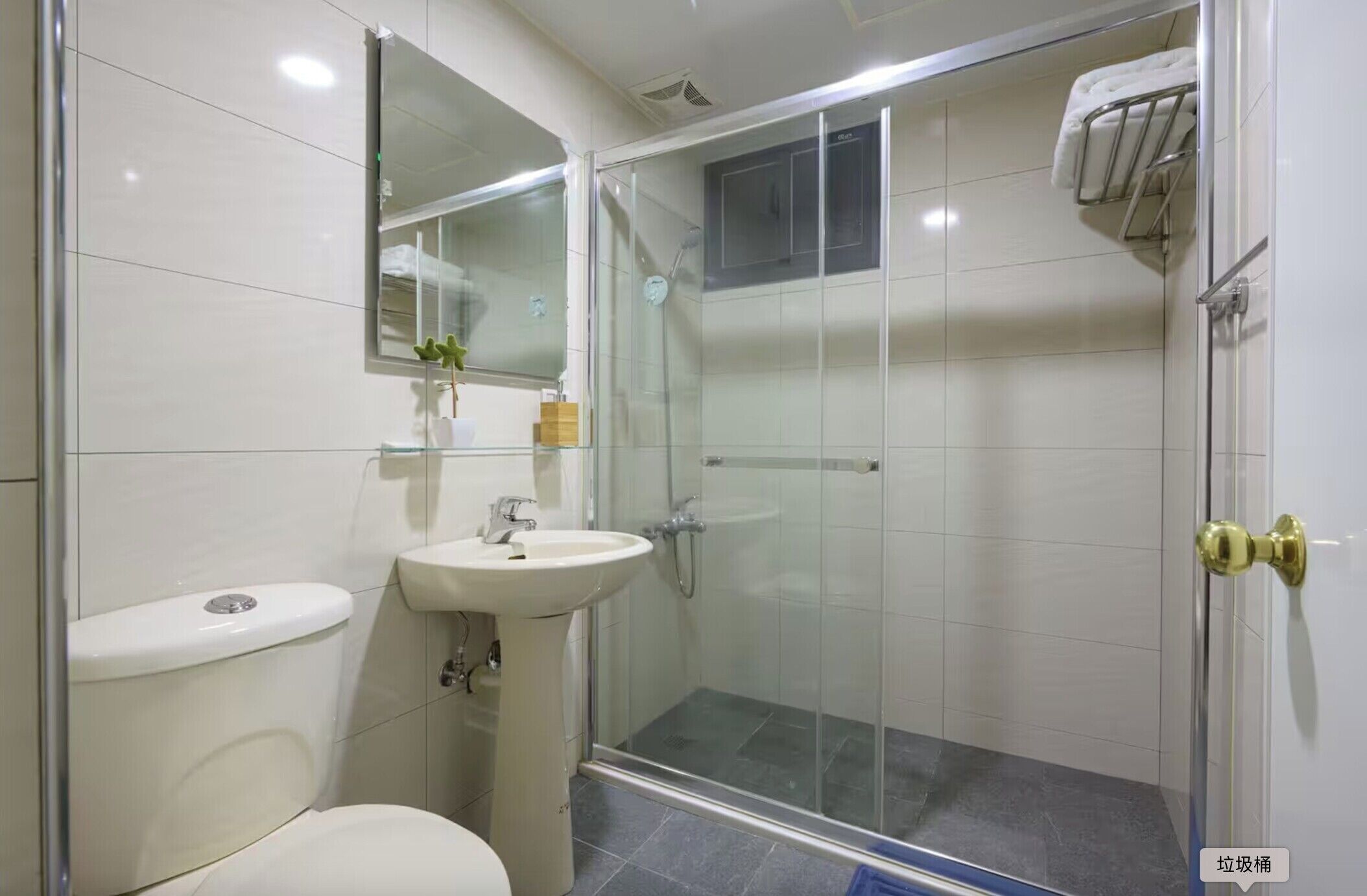 A modern bathroom with a toilet, sink, and glass-enclosed shower.