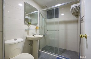 A modern bathroom with a toilet, sink, and glass-enclosed shower.
