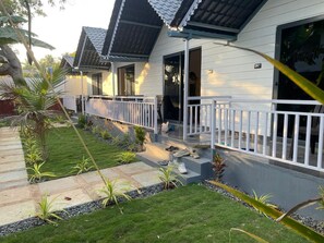 Ein modernes Haus mit überdachter Veranda, einem gepflegten Rasen und einem kleinen Garten.