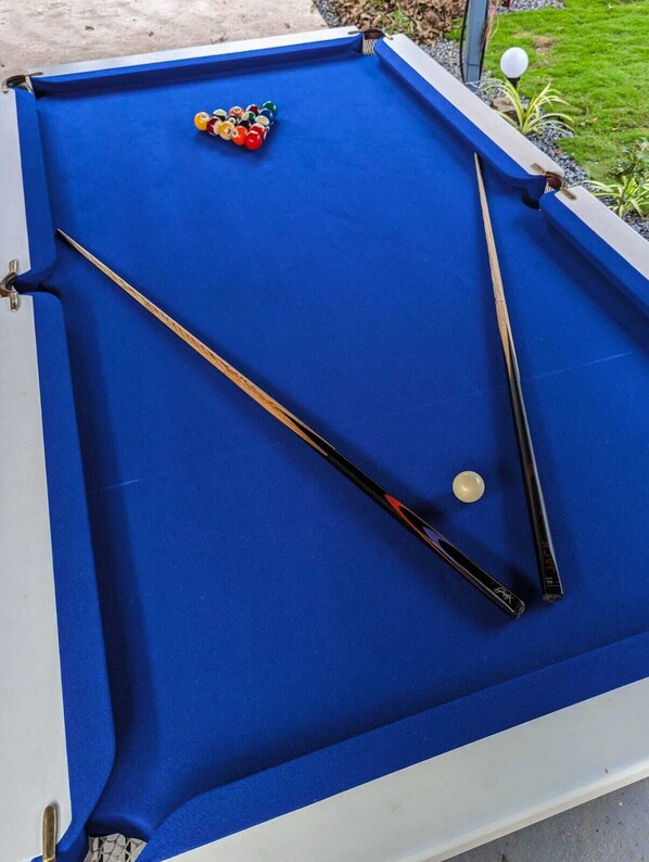 Ein blauer Billardtisch mit Billardstöcken und Kugeln.