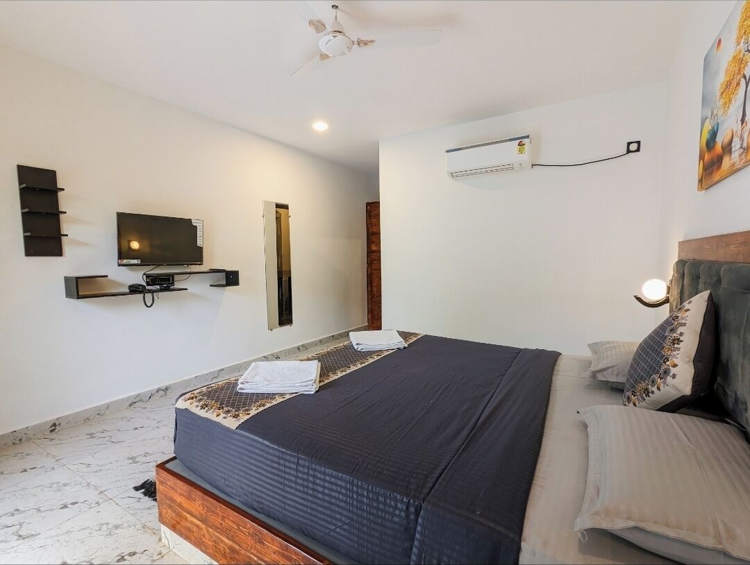 Ein Schlafzimmer mit Bett, Wandfernseher, Klimaanlage und Deckenventilator.