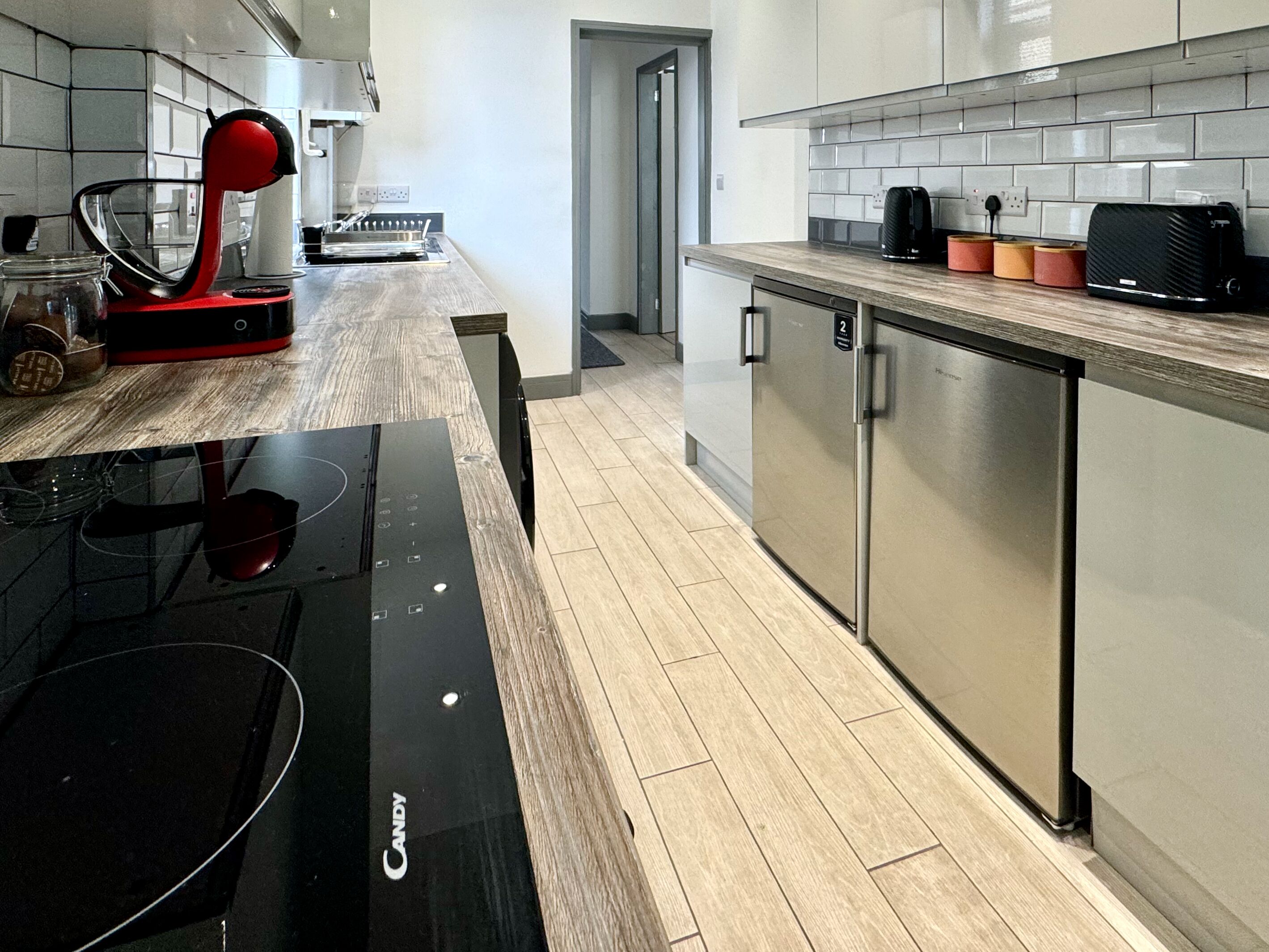 A modern kitchen with a black induction cooktop, stainless steel appliances, and a wooden countertop.