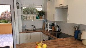 A modern kitchen with white cabinets, a wooden countertop, and a fruit bowl.