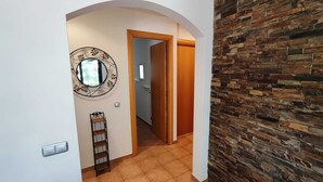 A hallway with a wooden door, a metal ladder, and a decorative circular mirror on the wall. - RURAL APARTMENT SOL BERGUEDA (Avià Barcelona)