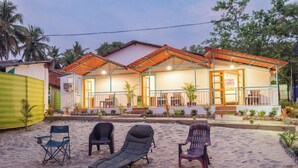 A beachfront property with a covered patio, lounge chairs, and a small pool area. - Olive Beach House (Canacona)