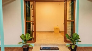 A doorway with a wooden frame, two potted plants on either side, and a small yellow cabinet in the background. - Olive Beach House (Canacona)