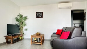 A living room with a TV, a sofa, a coffee table, and a plant.