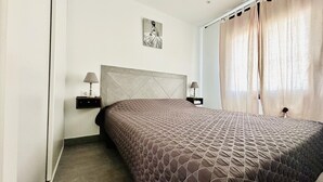 A bedroom with a large bed, two bedside tables with lamps, a headboard, and a painting on the wall.