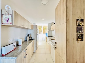 A modern kitchen with wooden cabinets, a built-in oven, a coffee maker, and a toaster.