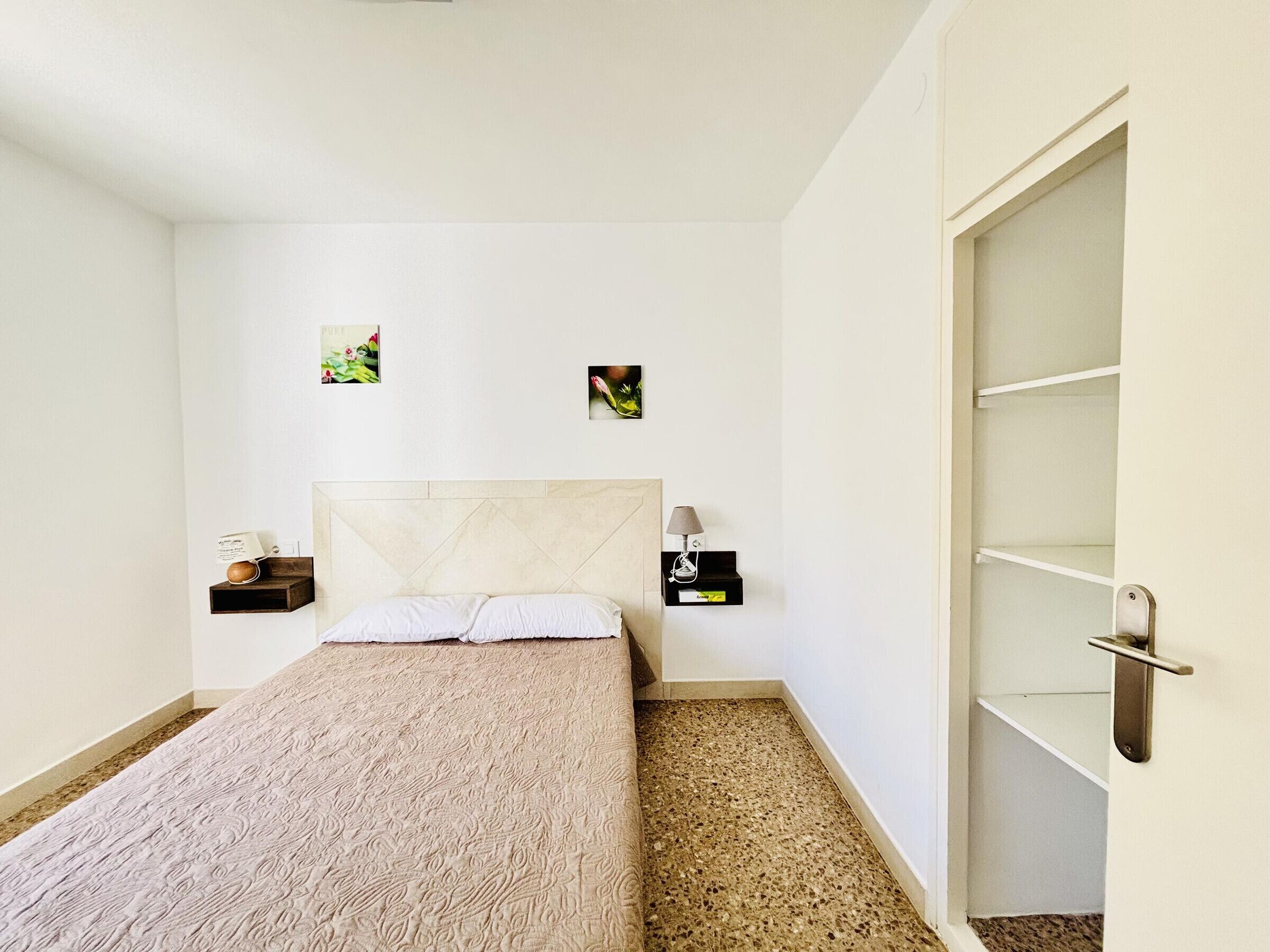 A bedroom with a bed, two bedside tables, a nightstand, a headboard, and a wardrobe.