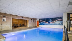 Una piscina interna con elemento d'acqua blu, pareti in legno e un grande murale raffigurante un nuotatore.