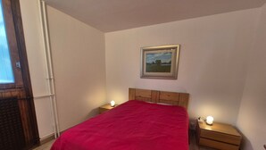 A bedroom with a wooden headboard, a red bedspread, two bedside tables with lamps, and a framed picture on the wall. - Comfortable apartment Tignes Val Claret, 5 pers, near slopes (Tignes)