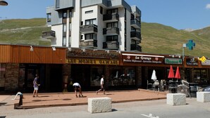A multi-story building with a restaurant named "Les Mômes Oa16 ANS" and a pharmacy. - Comfortable apartment Tignes Val Claret, 5 pers, near slopes (Tignes)