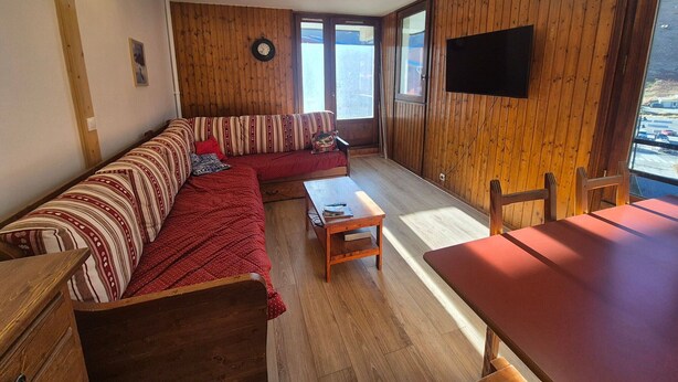 A cozy living room with a wooden floor, a striped sofa, a wooden table, and a large window. - Comfortable apartment Tignes Val Claret, 5 pers, near slopes (Tignes)