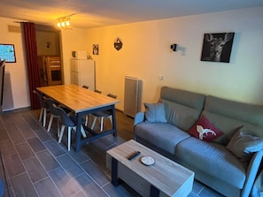 Een kleine woonruimte met een eettafel, stoelen, een bank en een salontafel.