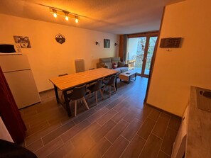Un espace de vie compact comprenant un coin repas, une kitchenette et un canapé à l’arrière-plan.