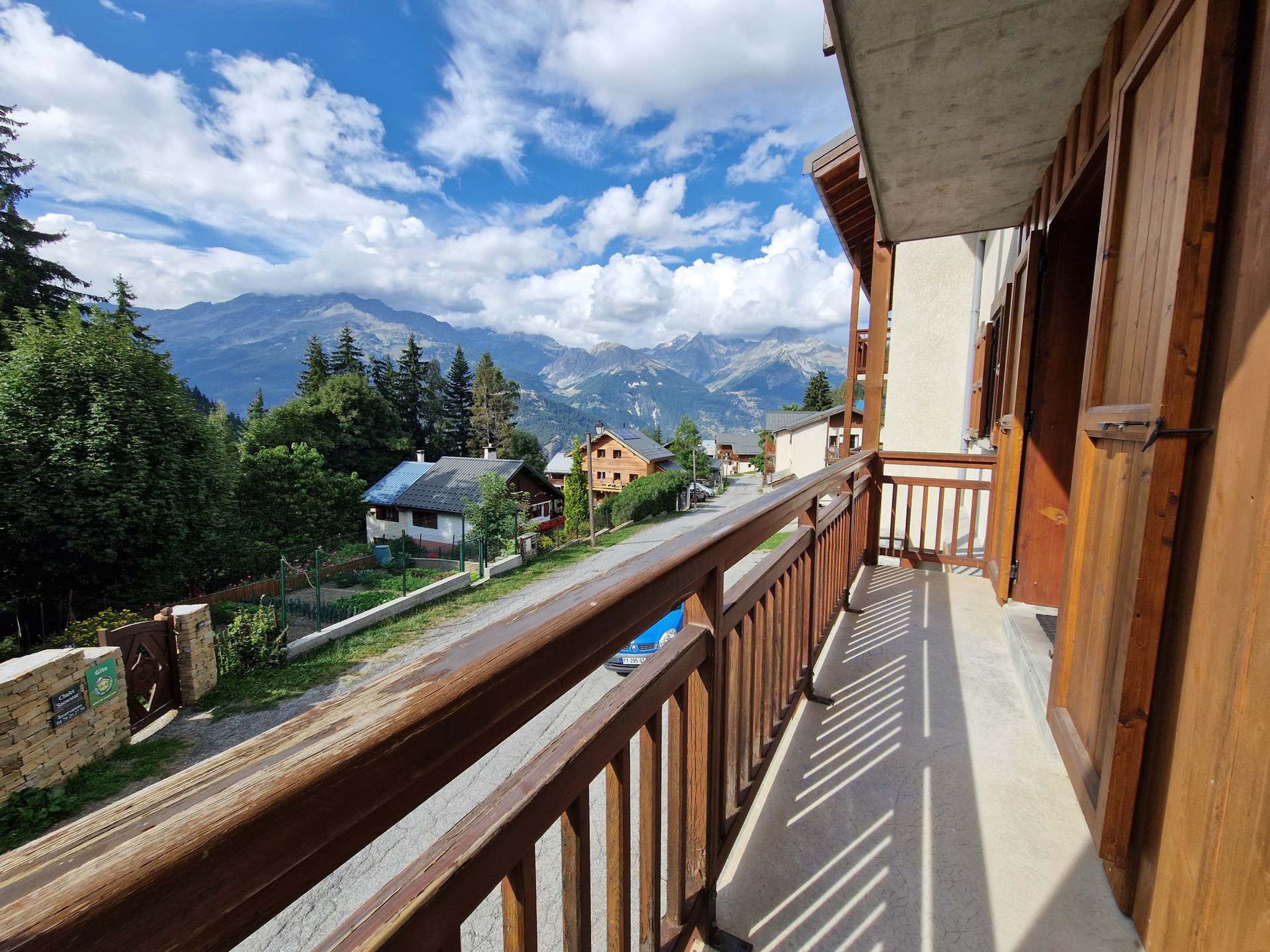 A balcony with a wooden railing overlooking a mountain landscape.