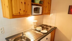A compact kitchen with wooden cabinets, a stainless steel sink, a microwave, a coffee maker, and a dishwasher. - 3-room apartment, 6 people, at the slopes, pets allowed (Valfréjus)