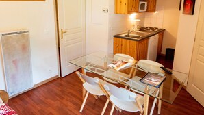A compact kitchen with wooden cabinets, a microwave, and a glass dining table with two chairs. - 3-room apartment, 6 people, at the slopes, pets allowed (Valfréjus)