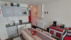 Une cuisine compacte avec des meubles blancs, un four à micro-ondes, une machine à café et un grille-pain.