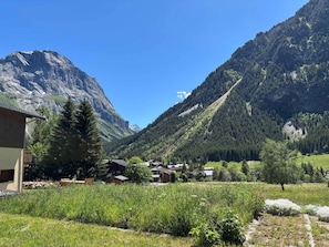 Eine gebirgige Landschaft mit einem Gebäude und Häusern im Tal.