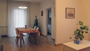Una zona de menjador amb una taula i cadires, un arbre de Nadal, una planta en test i un quadre al mur.