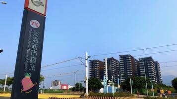 A sign for Danhai New Town Station with a V10 logo, surrounded by modern high-rise buildings and a clear sky.