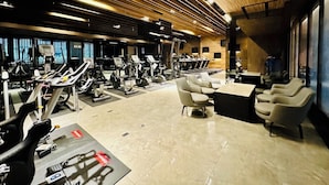Een moderne sportschool met cardioapparaten, gewichten en zithoeken.