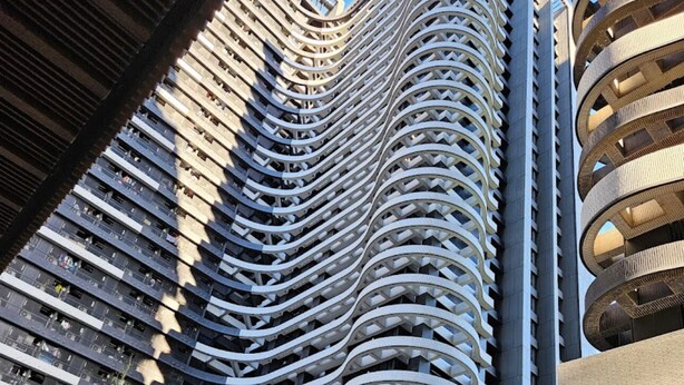 Een modern gebouw met een gebogen gevel en diverse balkons.