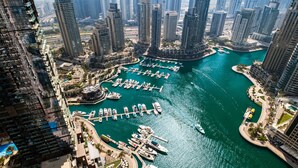 A marina with boats docked, surrounded by high-rise buildings.