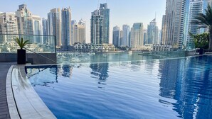 A modern infinity pool with a city skyline view, featuring high-rise buildings and a marina.
