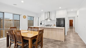 Una cucina moderna con isola centrale, tavolo da pranzo in legno e sedie.