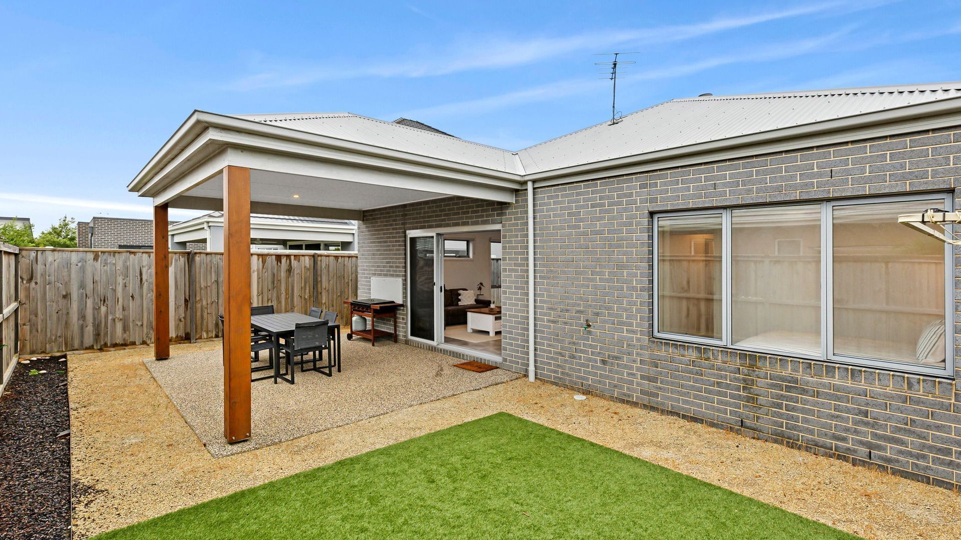 A residential property with a patio, a covered outdoor seating area, a brick exterior, and a sliding glass door leading to an interior space.