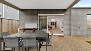 Une terrasse extérieure avec une table et des chaises, une clôture en bois et un mur en briques.
