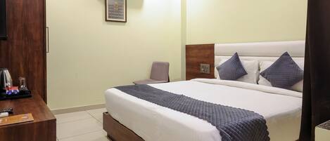 A hotel room with a bed, a desk, and a television.