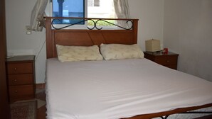 A bedroom with a wooden headboard, two pillows, a bedside table, and a window with curtains. - Morning Star Guesthouse (Sharm El Shikhe)