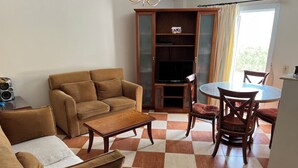 A living room with a sofa, a coffee table, and a glass-top dining table with chairs. - Morning Star Guesthouse (Sharm El Shikhe)