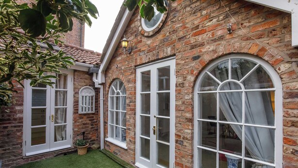 A brick building with white-framed windows and a small lawn area. - Monk Bar Garden Hideaway (York)