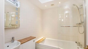 Een moderne badkamer met een glazen douchecabine, een wastafel en een toilet.