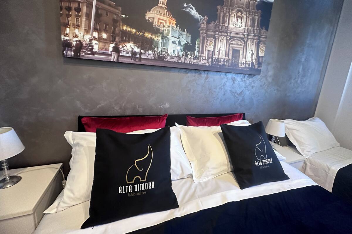 Ein Hotelzimmer mit Bett, Kissen, einem Nachttisch und einem Wandbild.