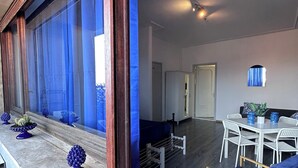 A modern interior with a dining area, a sofa, and a window with blue curtains. - ALTA DIMORA b&b suites (Catania)