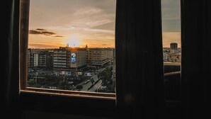 A view from a window of a cityscape at sunset, featuring a prominent building with a clock tower and several other high-rise buildings. - ALTA DIMORA b&b suites (Catania)