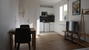 Ett kompakt bostadsutrymme med ett litet kök, en matplats och en tv.
